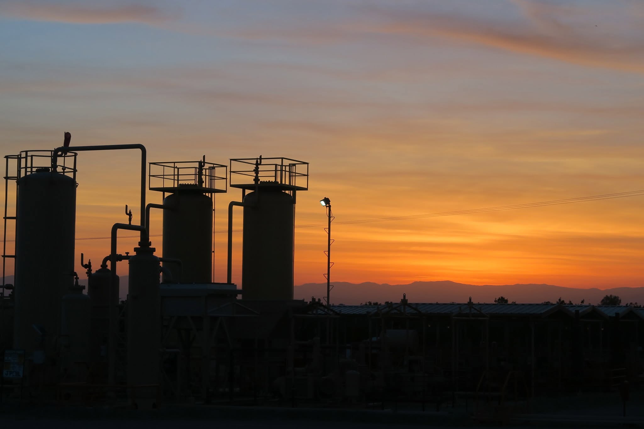Oil production equipment silhouetted against a sunset sky